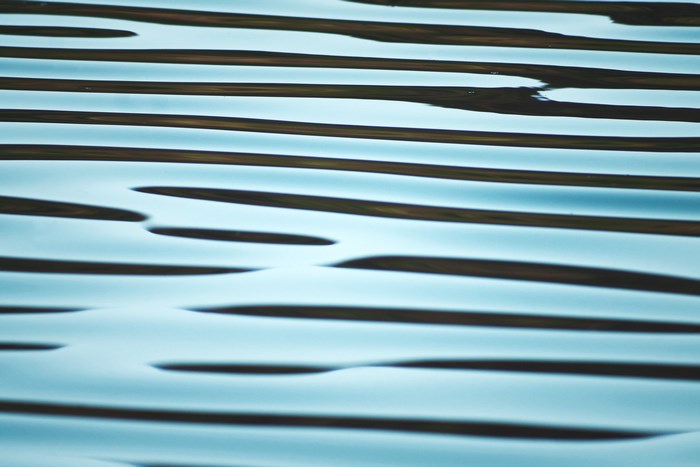 Abstract wavy blue water surface with dark lines