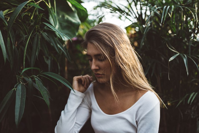 Woman with blonde hair in a white shirt surrounded by plants