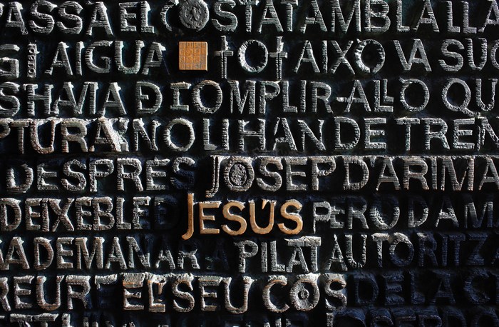 Jesus and other words carved into a dark textured surface