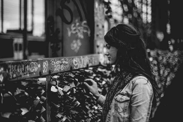 Woman touching love locks on a graffiti-covered bridge