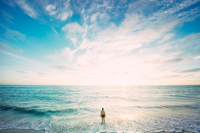 Woman standing in the ocean at sunset