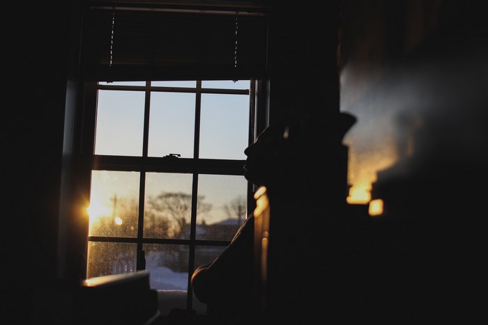 Silhouette of a person looking out a window at sunrise