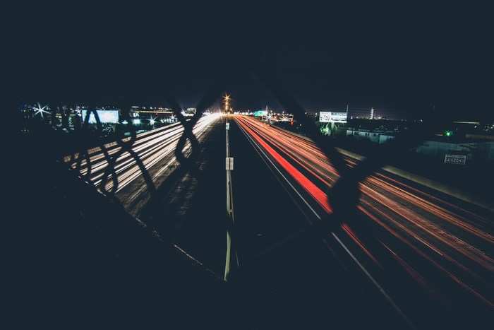Highway at night with light trails and fence