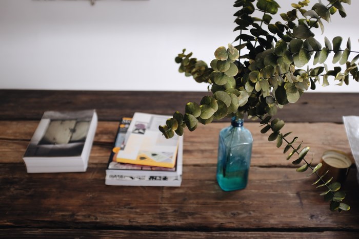 Books and eucalyptus in a blue vase on a wooden table