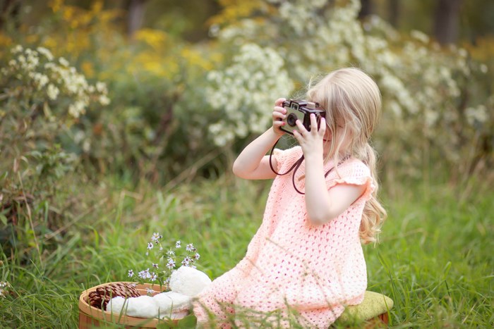 Girl holding a vintage camera in a grassy field
