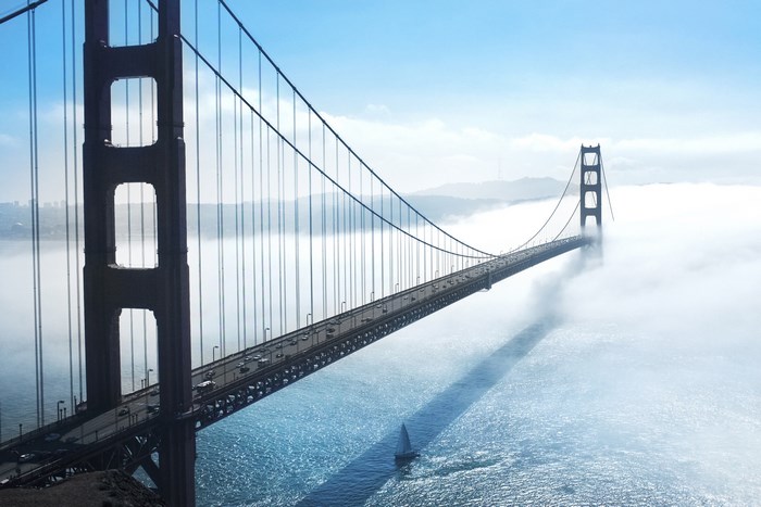 Golden Gate Bridge shrouded in fog with a sailboat