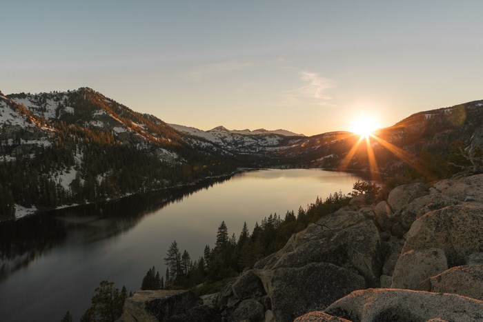 Sunset over a snow-capped mountain lake with rocks