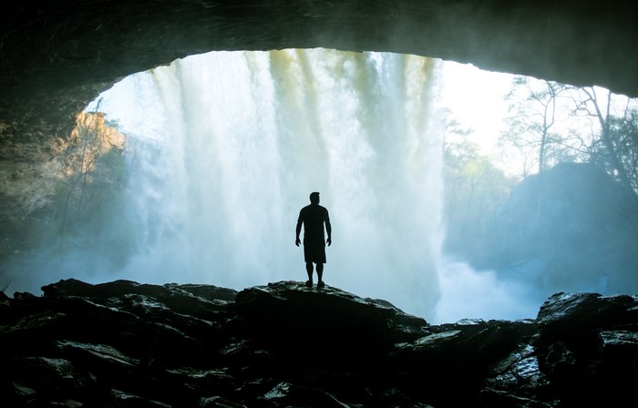 Silhouette of a person in a cave behind a waterfall in Alabama