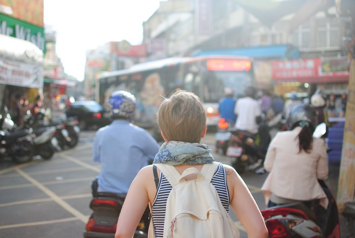 Woman with backpack on a busy street with motorcycles and bus