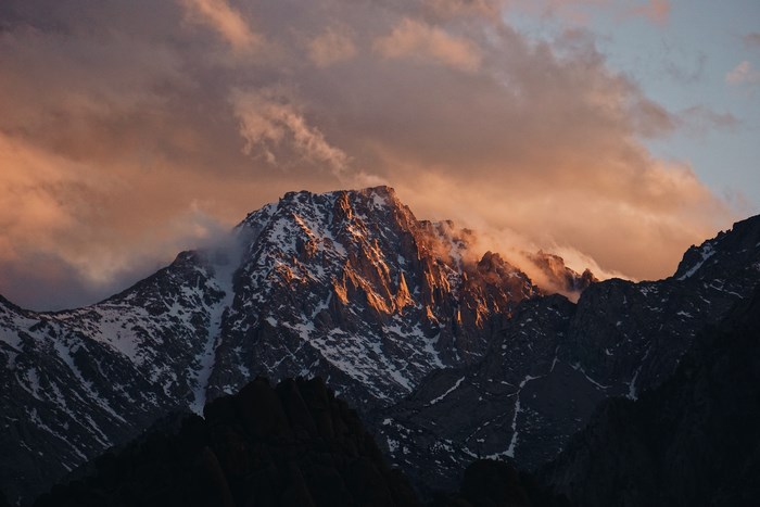 Snow-capped mountains at sunset with clouds