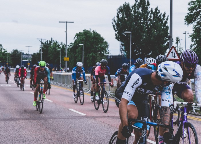 Cyclists racing on a street with trees and barriers