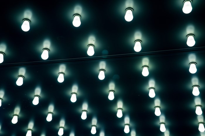 Repetitive pattern of illuminated light bulbs on a dark surface
