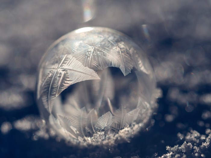 Frozen bubble with frost patterns on snow