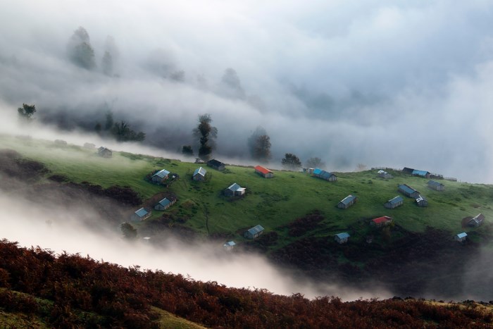 Foggy Gilan hillside village with scattered houses and trees