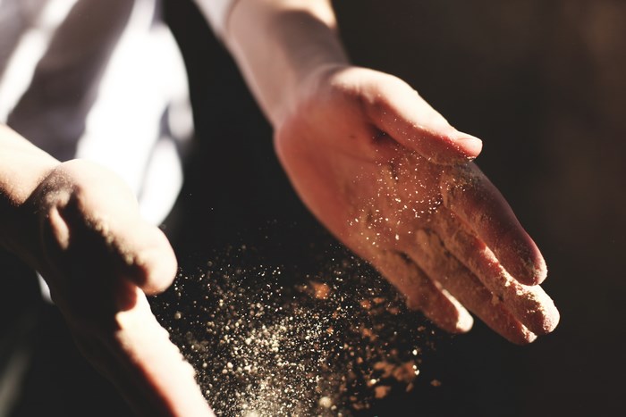 Hands scattering dust particles in sunlight