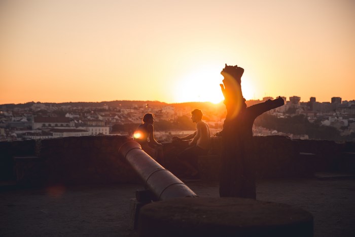 Couple watching sunset over Lisbon from a fort with a cannon