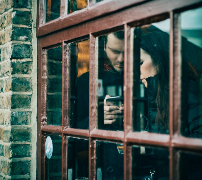 Couple looking at a phone through a window