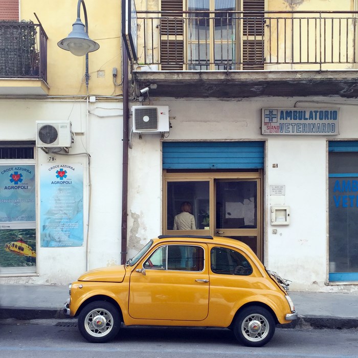 Yellow Fiat 500 parked in front of a veterinary clinic
