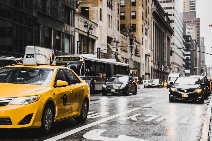 Yellow taxi and bus on a rainy New York City street
