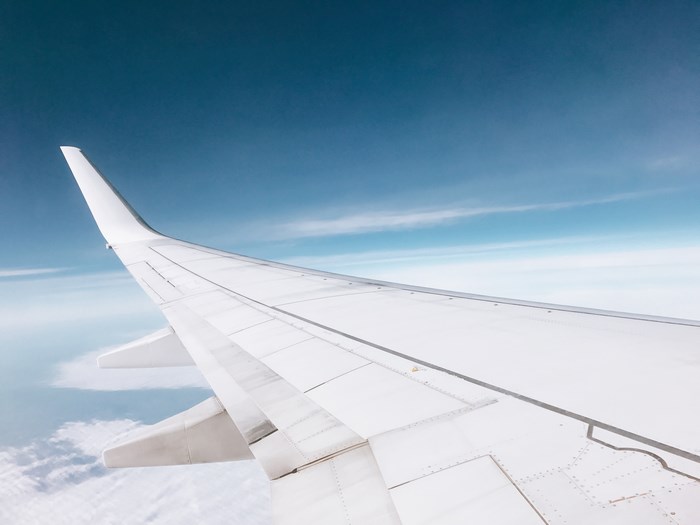 Airplane wing against a blue sky and clouds