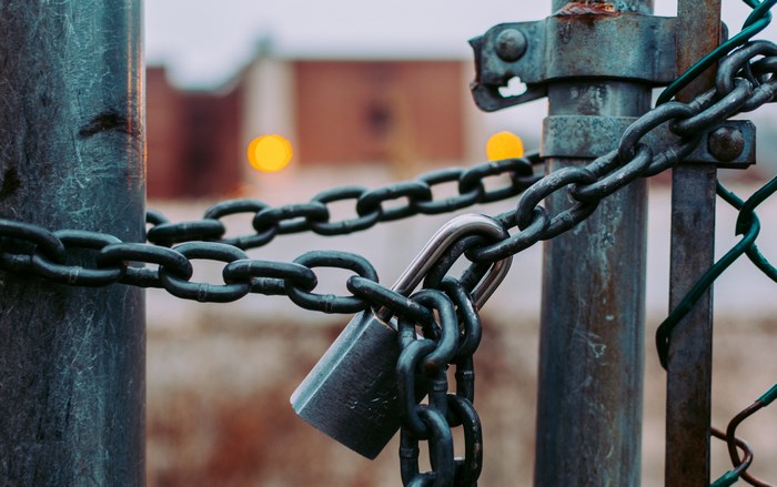Padlock and chain securing a rusty metal gate