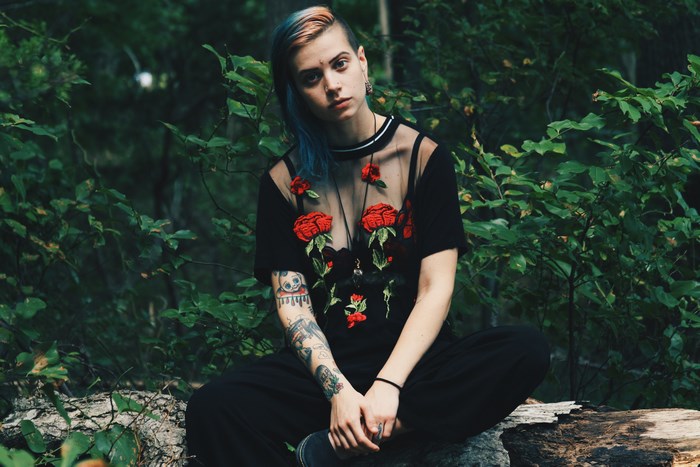 Woman with blue hair and tattoos in forest