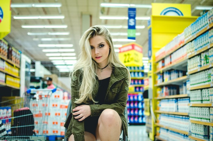 Woman in a green jacket in a supermarket aisle