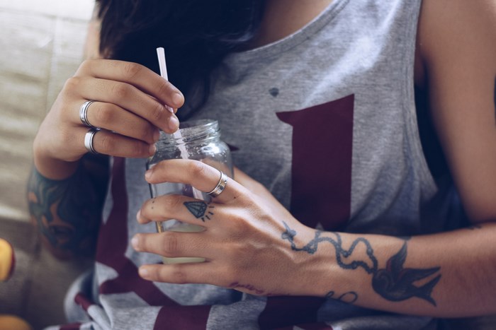Woman with tattoos holding a glass with a straw