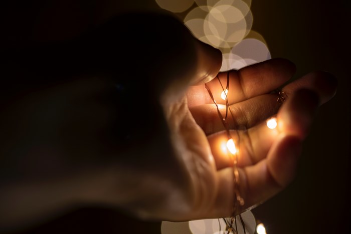Hand holding glowing fairy lights with bokeh background