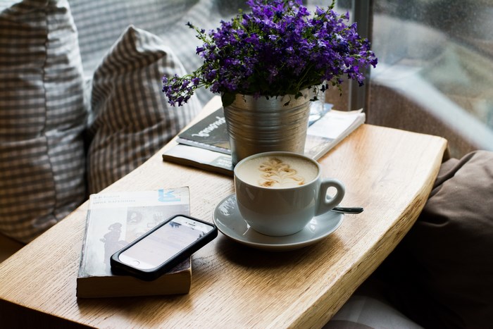 Coffee cup with flowers and a book on a wooden table
