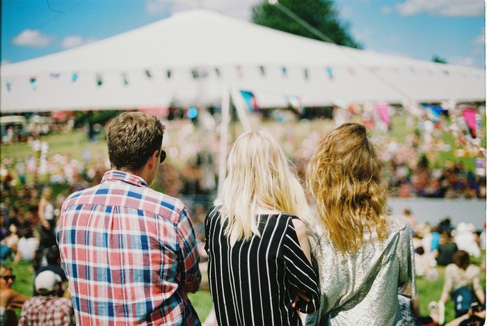 Three people at a music festival under a tent
