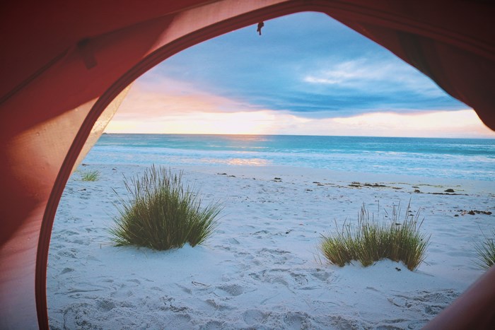 View from a tent of a beach at sunset