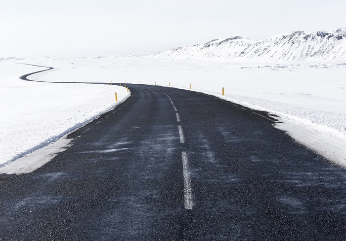 Winding asphalt road through a snowy landscape