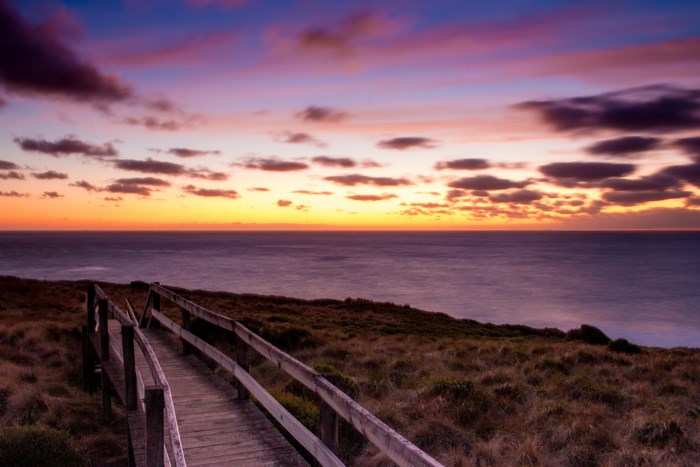 Wooden boardwalk overlooking the ocean at sunset