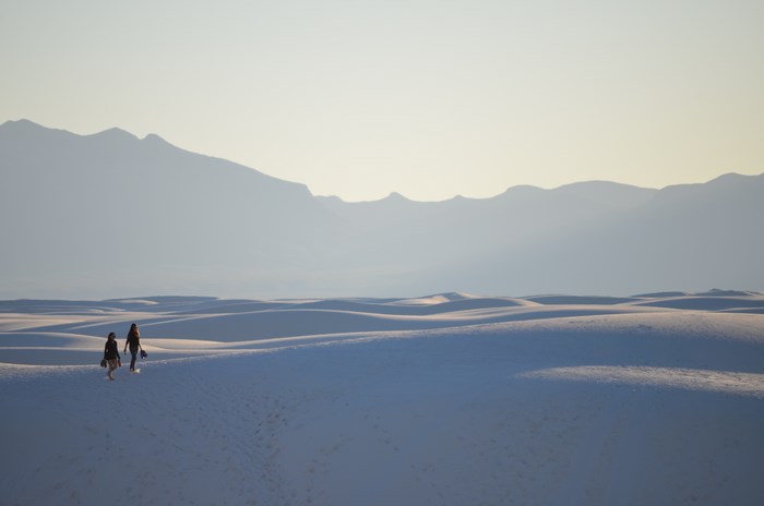 Two people walking on white sand dunes in New Mexico