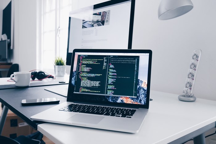 Mac laptop and desktop computer setup with coding