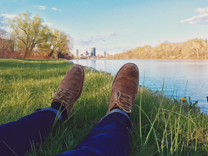 Person relaxing by a river with city skyline in background