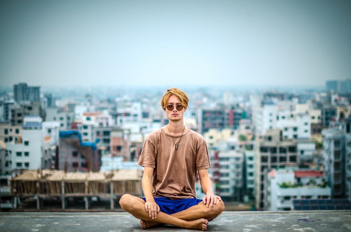 Man meditating on a rooftop overlooking a city
