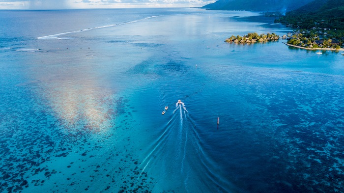 Boat sailing in a clear blue ocean near a tropical island