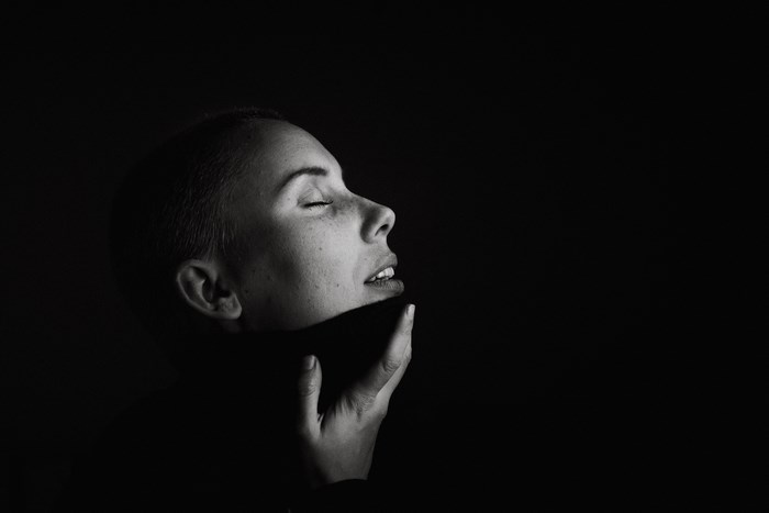Woman with eyes closed touching her chin