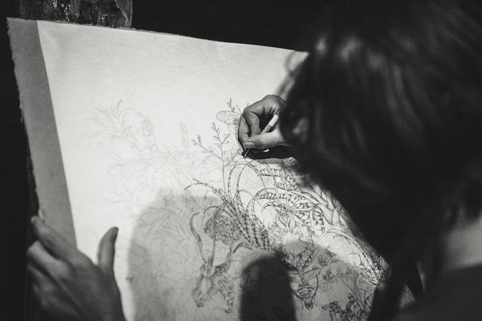 Artist drawing a detailed floral sketch in black and white