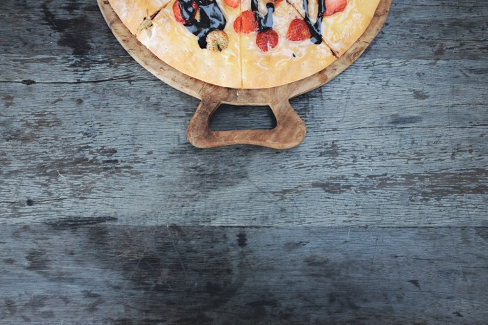 Strawberry pizza with chocolate sauce on a wooden board