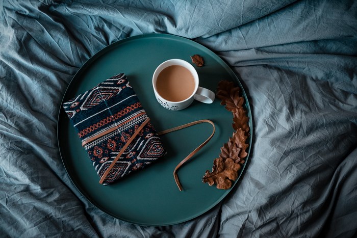 Flatlay of a book, mug, and leaves on a tray