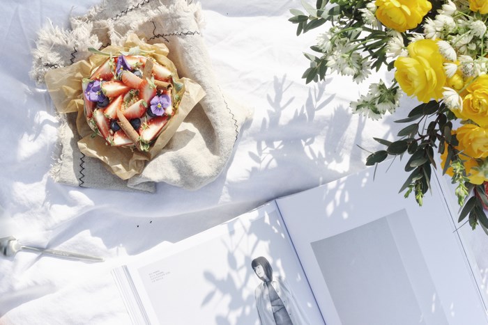 Strawberry tart with flowers and a book on a white cloth