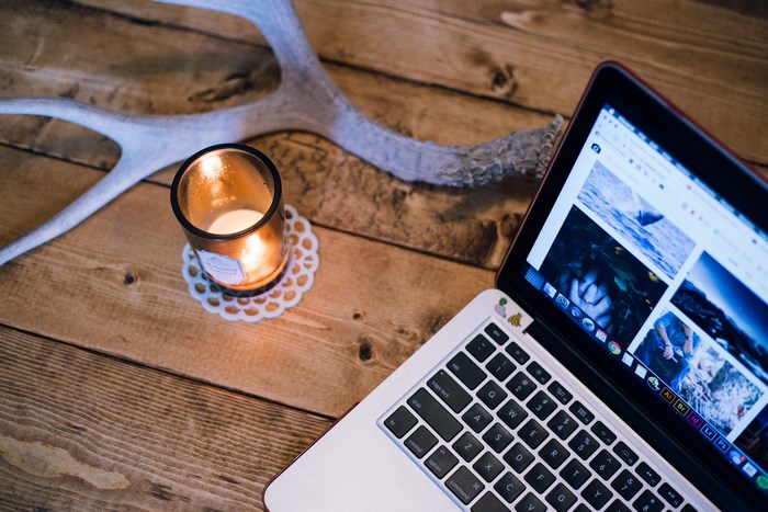 Laptop and candle on a wooden table with antler