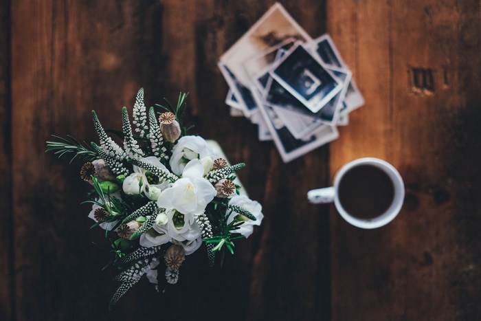Bouquet of white flowers and photos on a wooden table