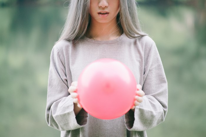 Woman holding a pink balloon with grey hair