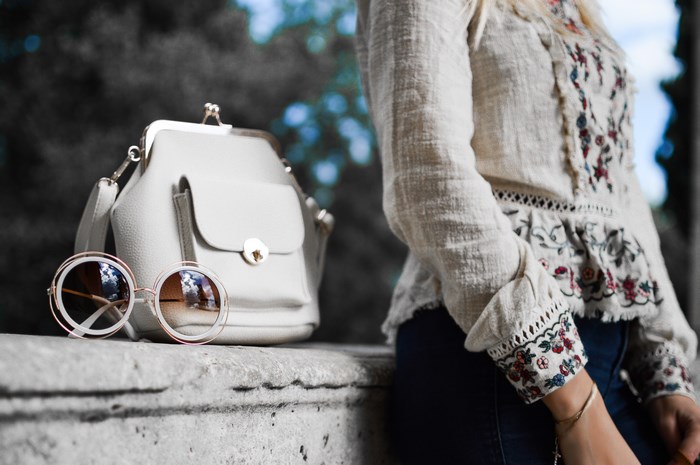 Woman with embroidered blouse, handbag, and sunglasses