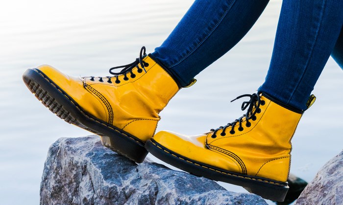 Yellow Dr. Martens boots on rocks near water