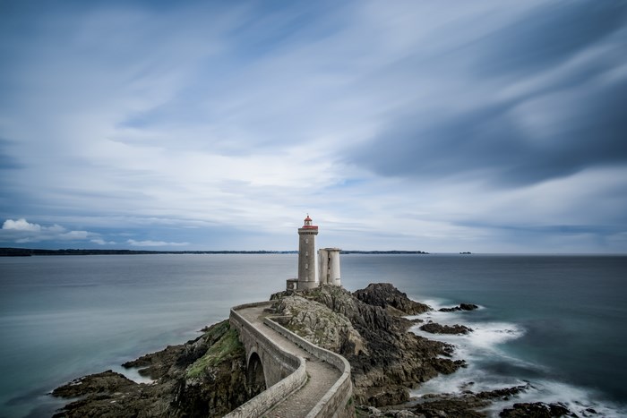 Lighthouse on a rocky island with a bridge